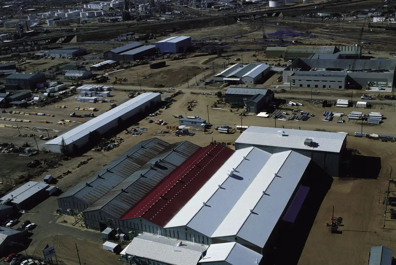 Aerial view of a large industrial complex with long warehouse buildings and metal roofs
