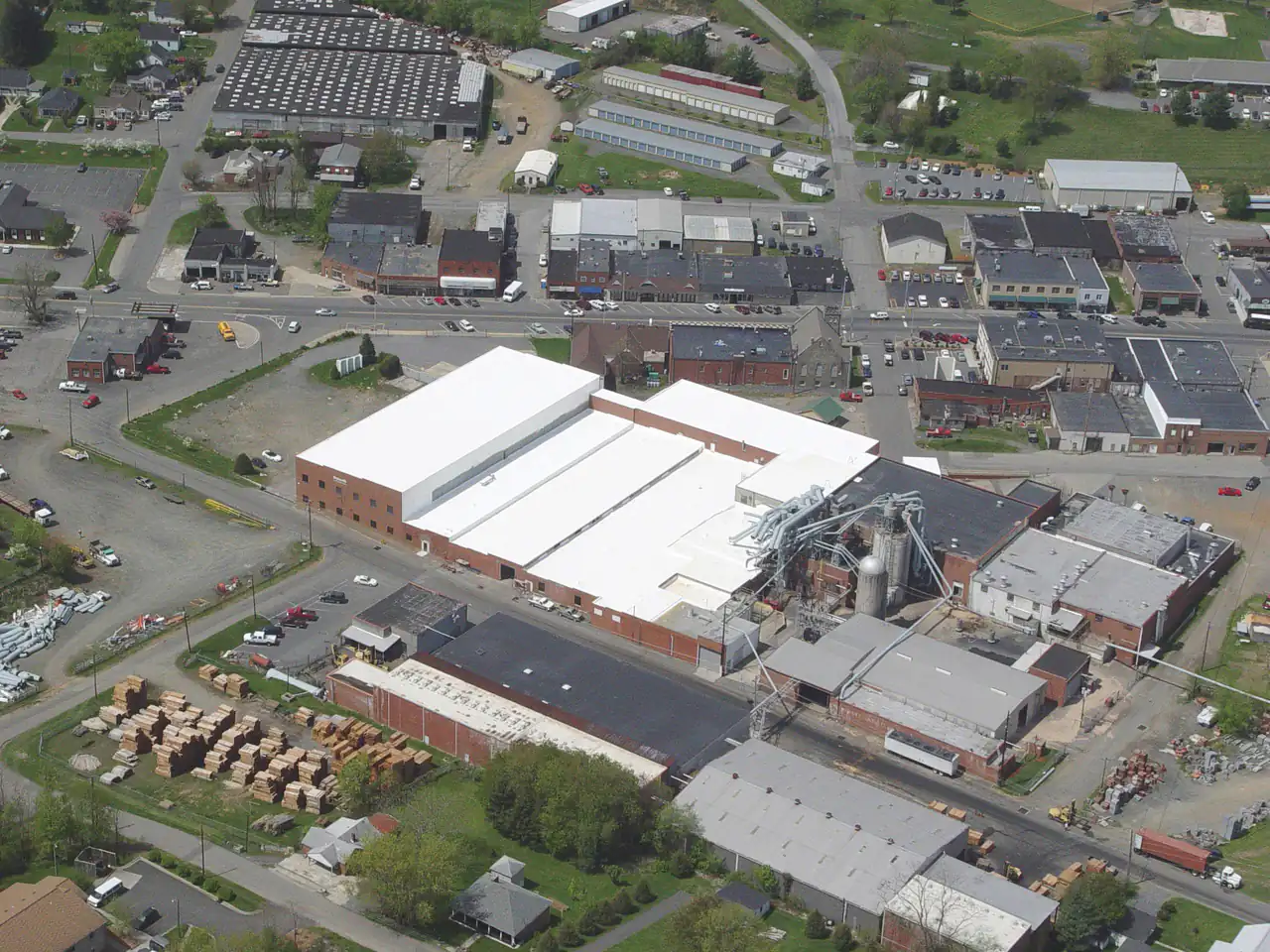 Aerial view of a manufacturing plant with white roofs surrounded by a small town