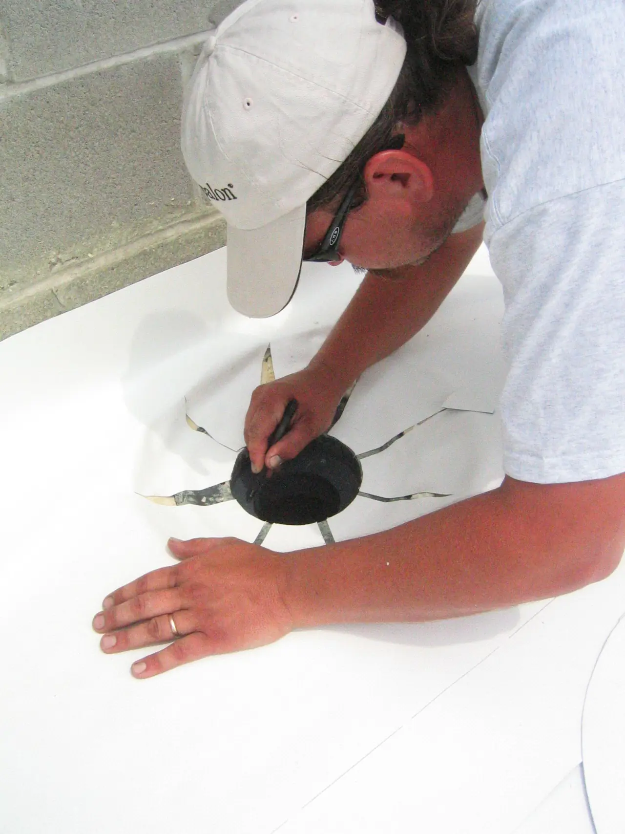 A roofer sealing the flashing around a roof drain on a white roof