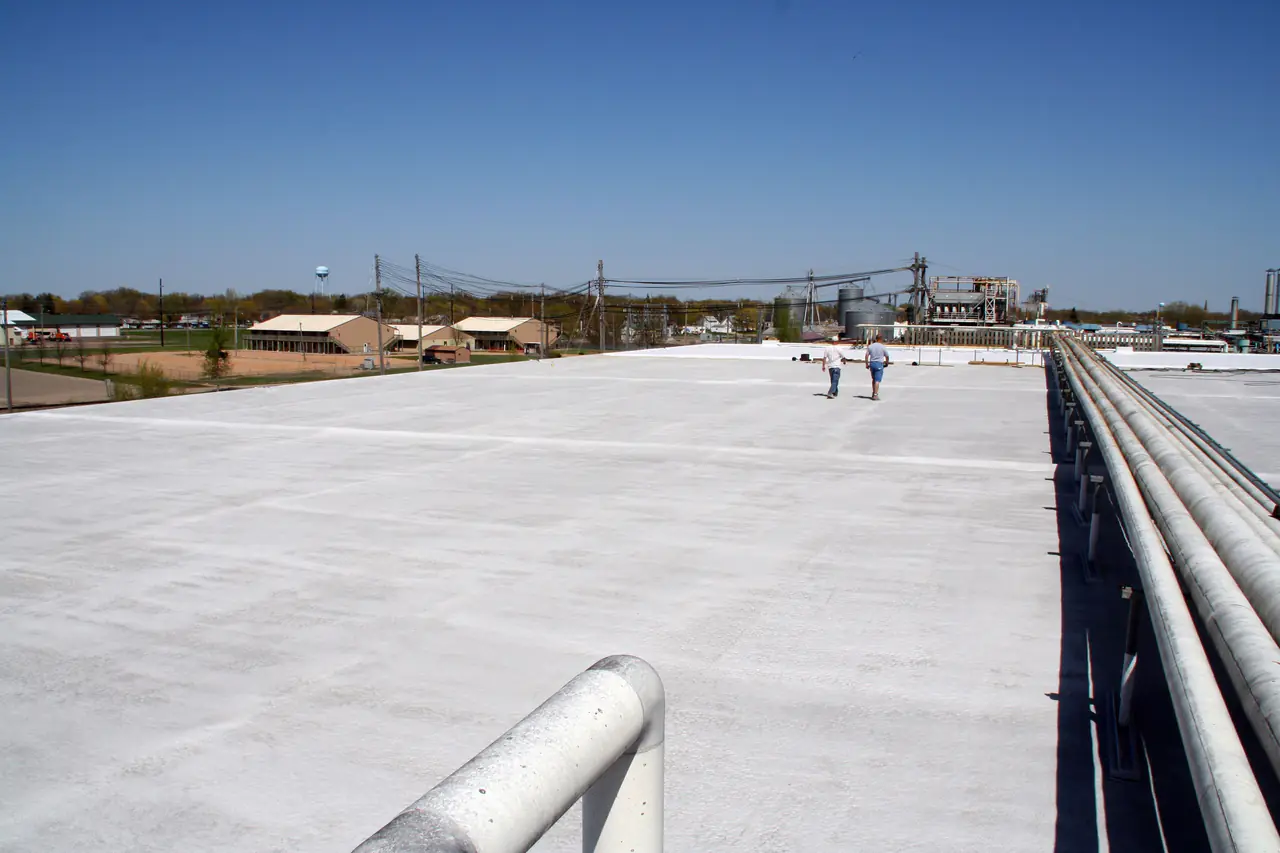 A large white flat roof on an industrial building under a clear blue sky